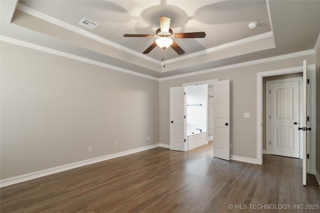 unfurnished bedroom featuring dark wood-type flooring, ceiling fan, connected bathroom, a tray ceiling, and ornamental molding