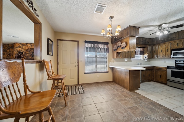 kitchen with pendant lighting, stainless steel appliances, kitchen peninsula, and light tile patterned floors