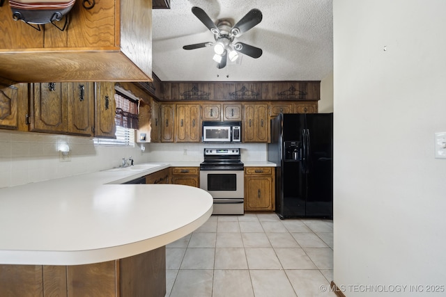 kitchen featuring sink, a textured ceiling, light tile patterned floors, appliances with stainless steel finishes, and kitchen peninsula