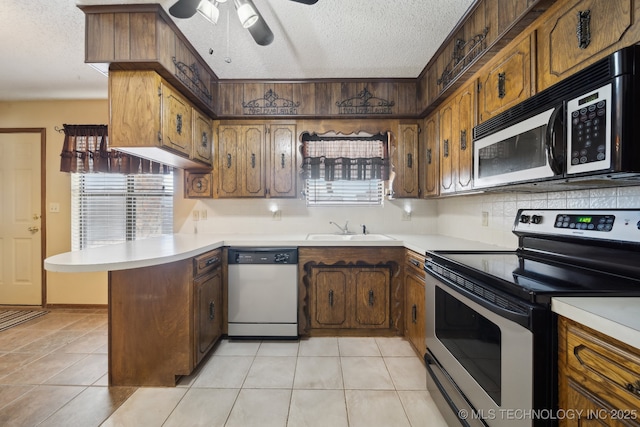 kitchen with sink, stainless steel appliances, a textured ceiling, light tile patterned flooring, and kitchen peninsula