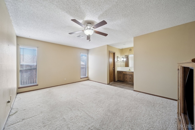 interior space with sink, ceiling fan, connected bathroom, a textured ceiling, and light carpet