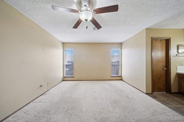 carpeted empty room featuring ceiling fan and a textured ceiling