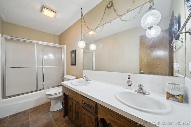 full bathroom featuring combined bath / shower with glass door, decorative backsplash, vanity, toilet, and a textured ceiling