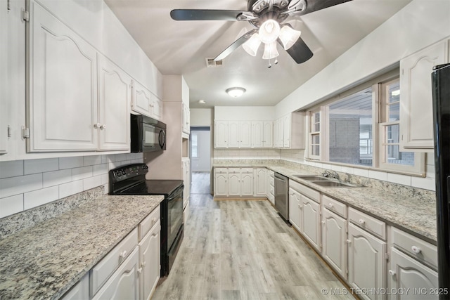 kitchen with tasteful backsplash, sink, white cabinets, black appliances, and light wood-type flooring