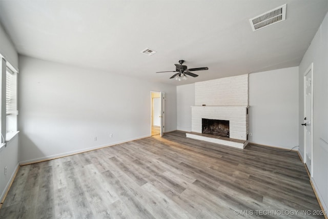 unfurnished living room with ceiling fan, wood-type flooring, and a brick fireplace