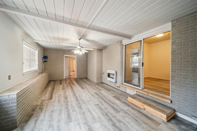 unfurnished living room with beam ceiling, brick wall, heating unit, and light wood-type flooring