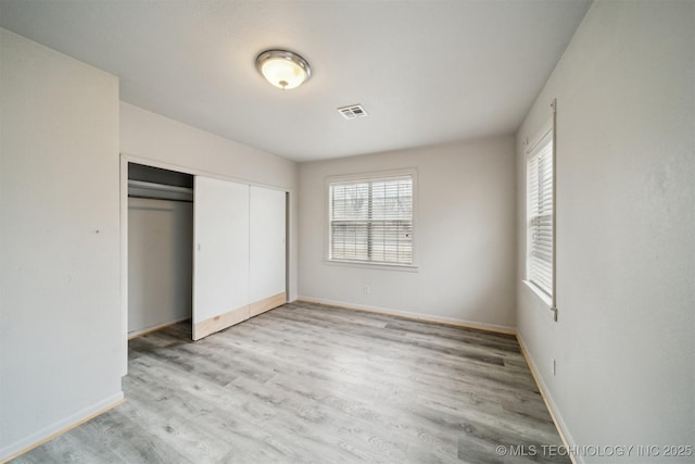 unfurnished bedroom with light wood-type flooring and a closet