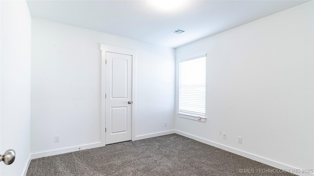 unfurnished room featuring dark carpet