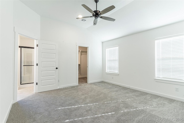 unfurnished bedroom featuring vaulted ceiling, a walk in closet, light carpet, and a closet