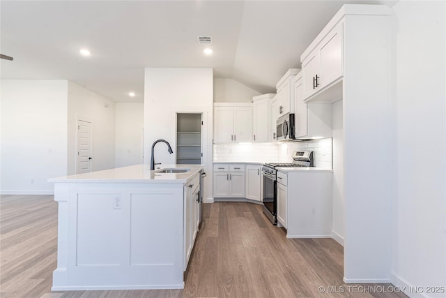 kitchen featuring sink, tasteful backsplash, a center island with sink, stainless steel appliances, and white cabinets