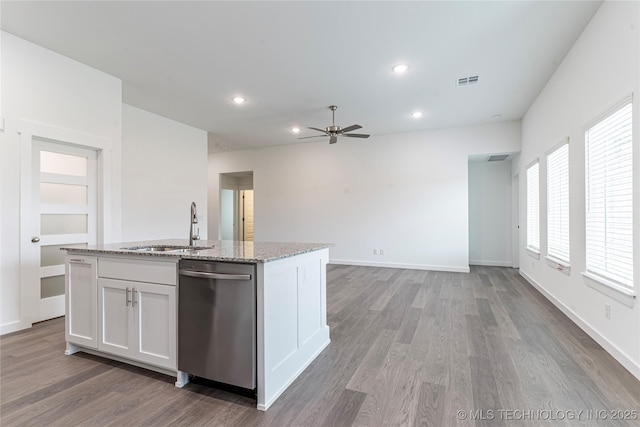 kitchen featuring dark hardwood / wood-style floors, white cabinetry, an island with sink, stainless steel dishwasher, and light stone countertops