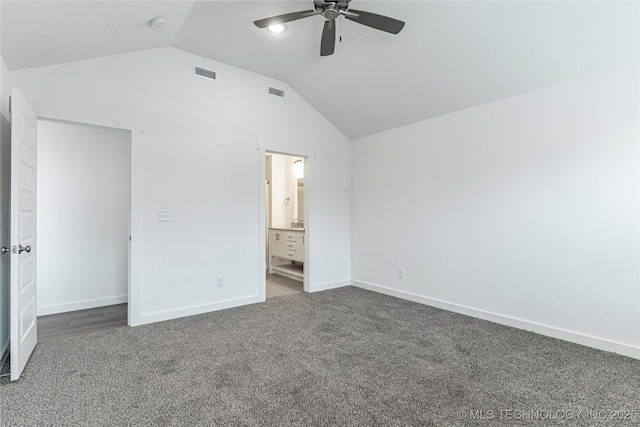 unfurnished bedroom featuring lofted ceiling, connected bathroom, dark carpet, and ceiling fan