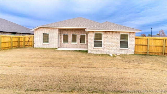 rear view of house with a patio and a lawn