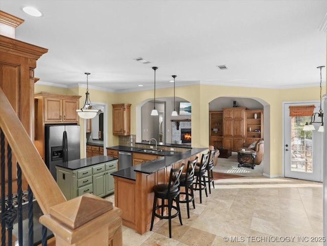 kitchen with sink, appliances with stainless steel finishes, a kitchen bar, decorative light fixtures, and kitchen peninsula