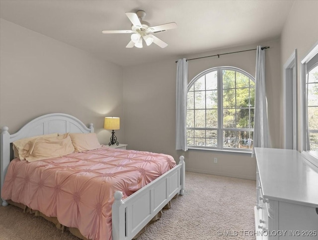 bedroom with multiple windows, light colored carpet, and ceiling fan