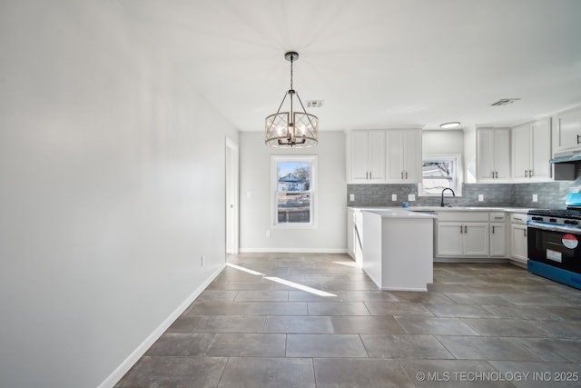 kitchen with sink, white cabinetry, hanging light fixtures, stainless steel range with gas stovetop, and decorative backsplash