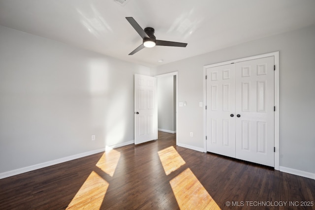 unfurnished bedroom with dark hardwood / wood-style flooring, a closet, and ceiling fan