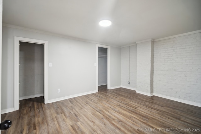 unfurnished bedroom featuring wood-type flooring and brick wall