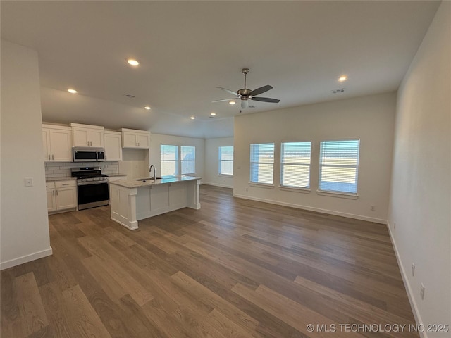 kitchen featuring appliances with stainless steel finishes, tasteful backsplash, sink, white cabinets, and a kitchen island with sink