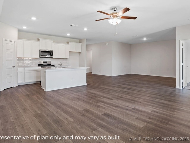 kitchen with appliances with stainless steel finishes, white cabinetry, dark hardwood / wood-style floors, tasteful backsplash, and a center island with sink