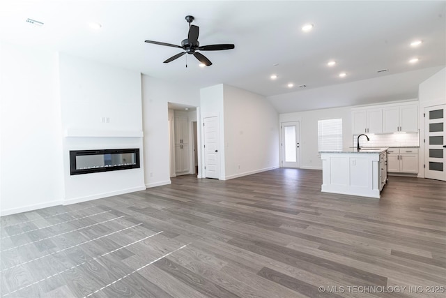 unfurnished living room with recessed lighting, a sink, a ceiling fan, light wood-type flooring, and a glass covered fireplace