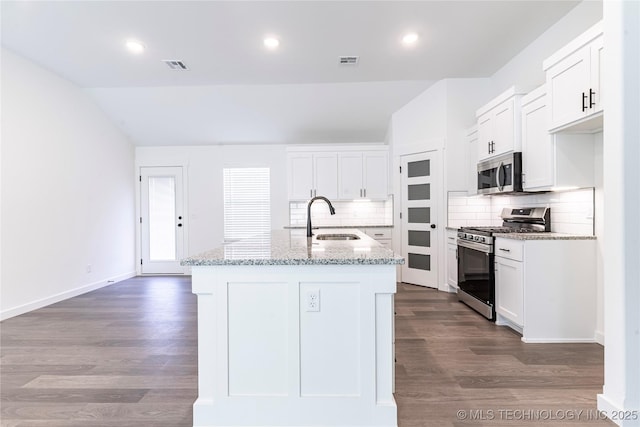 kitchen featuring visible vents, an island with sink, appliances with stainless steel finishes, white cabinetry, and a sink