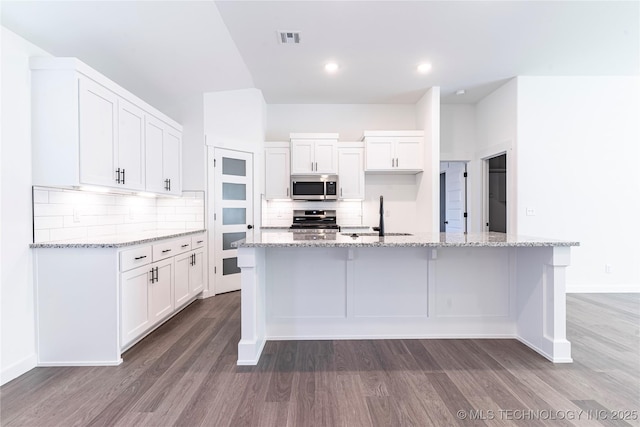 kitchen featuring appliances with stainless steel finishes, white cabinets, a kitchen island with sink, and a sink