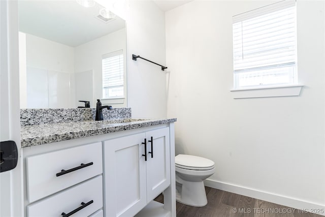 bathroom with visible vents, baseboards, toilet, wood finished floors, and vanity