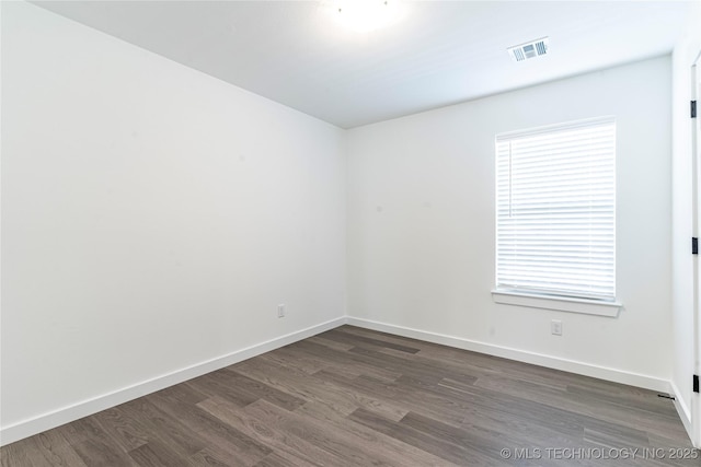 spare room with baseboards, visible vents, and dark wood-style flooring