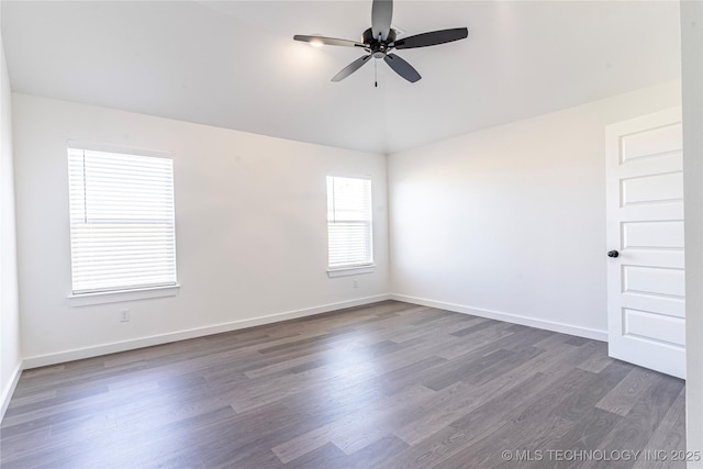 empty room featuring dark wood-type flooring, a ceiling fan, and baseboards