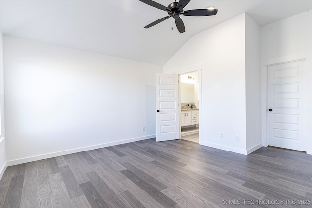 unfurnished bedroom featuring lofted ceiling, dark wood-style flooring, and baseboards