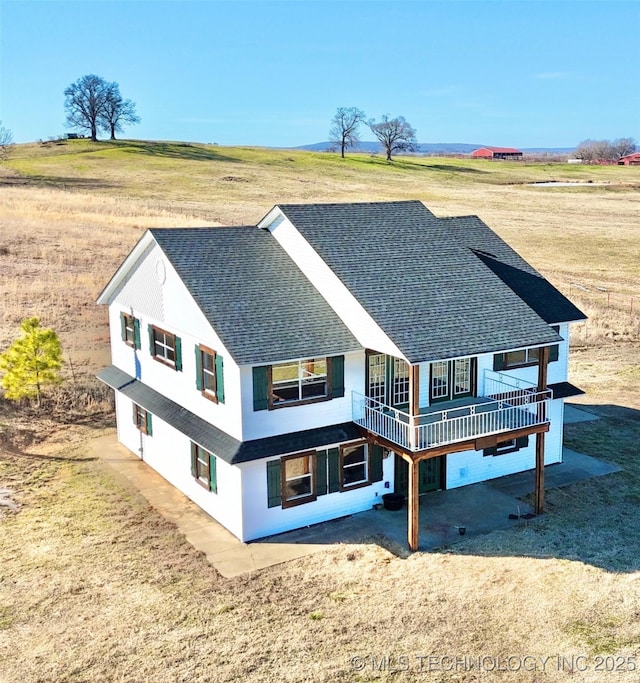 back of property featuring a deck, a lawn, and a rural view