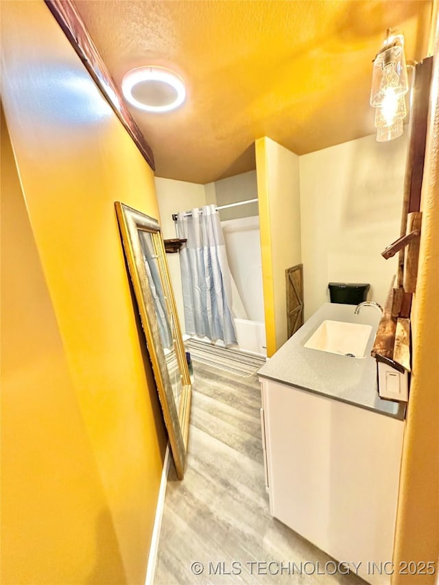 bathroom with shower / tub combo, vanity, wood-type flooring, and a textured ceiling