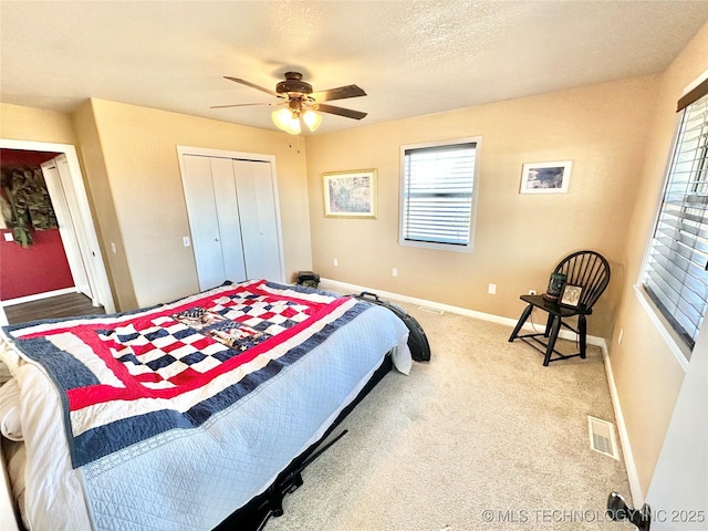 carpeted bedroom featuring ceiling fan, a textured ceiling, and a closet