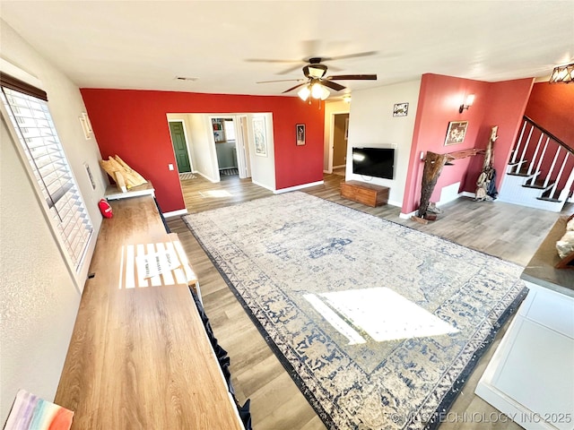 610 SW 7th Rd, Stigler, OK 74462 - unfurnished living room featuring wood finished floors, baseboards, a ceiling fan, and stairway