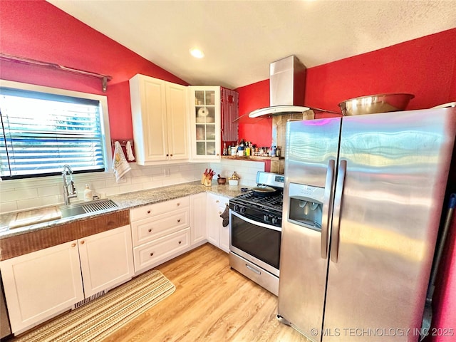 610 SW 7th Rd, Stigler, OK 74462 - kitchen featuring tasteful backsplash, light wood-type flooring, wall chimney range hood, lofted ceiling, and stainless steel appliances