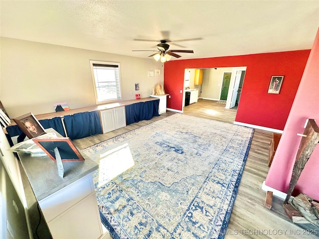 living room with ceiling fan, light hardwood / wood-style floors, and a textured ceiling