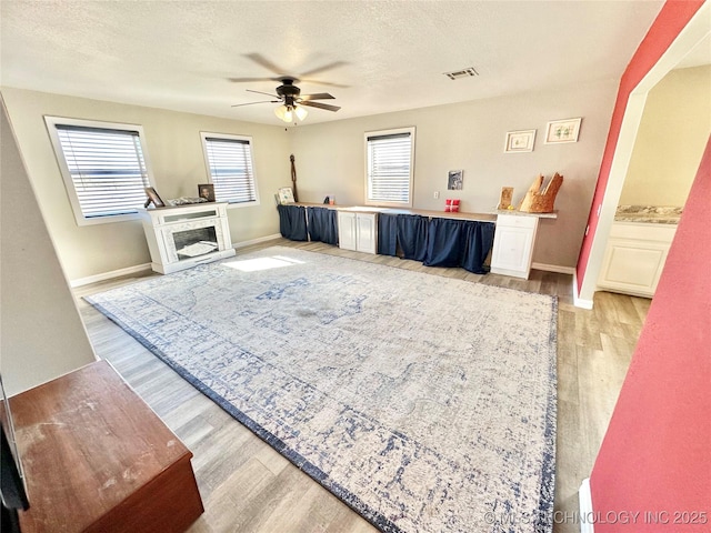 living room featuring ceiling fan, light hardwood / wood-style flooring, and a textured ceiling