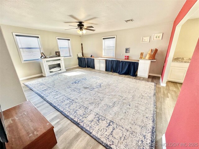 610 SW 7th Rd, Stigler, OK 74462 - living area featuring ceiling fan, a textured ceiling, visible vents, light wood finished floors, and baseboards