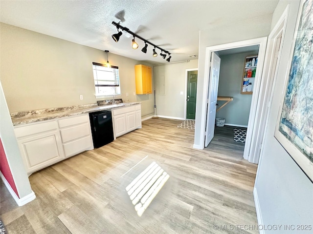 kitchen with light stone counters, a textured ceiling, light wood-type flooring, dishwasher, and white cabinets