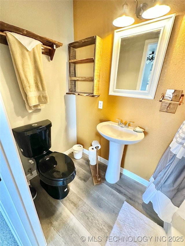 610 SW 7th Rd, Stigler, OK 74462 - bathroom featuring a sink, toilet, wood finished floors, and baseboards