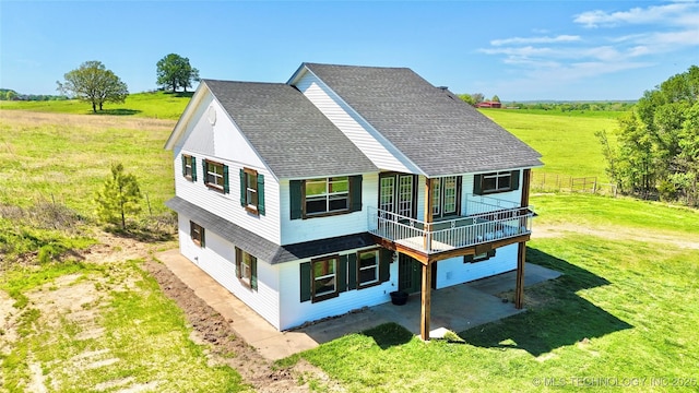 610 SW 7th Rd, Stigler, OK 74462 - rear view of house featuring a rural view, a shingled roof, a patio area, and a lawn