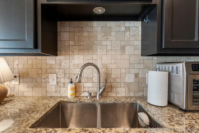 kitchen with tasteful backsplash, sink, and light stone countertops