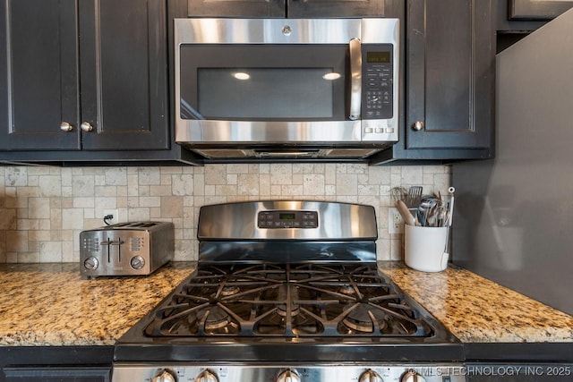 kitchen featuring appliances with stainless steel finishes, light stone countertops, and decorative backsplash