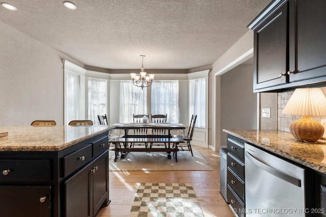 kitchen featuring light hardwood / wood-style flooring, dishwasher, light stone countertops, decorative backsplash, and a chandelier