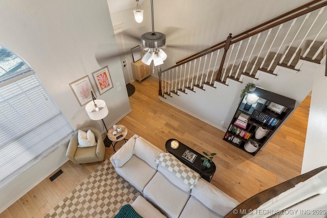 living room featuring ceiling fan, a towering ceiling, and light wood-type flooring