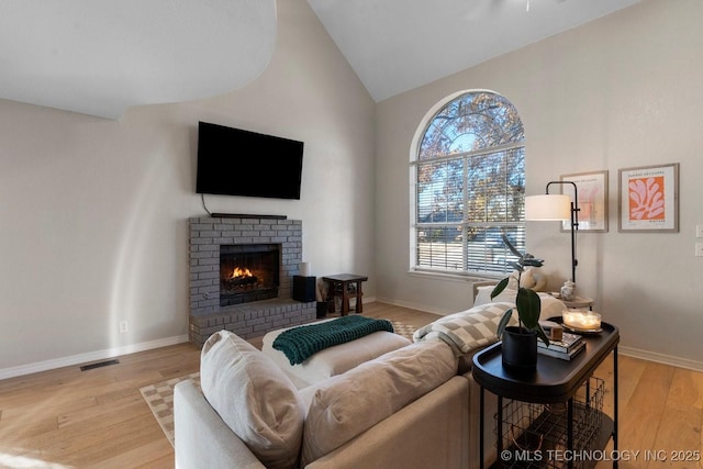 living room with a fireplace, vaulted ceiling, and light hardwood / wood-style flooring