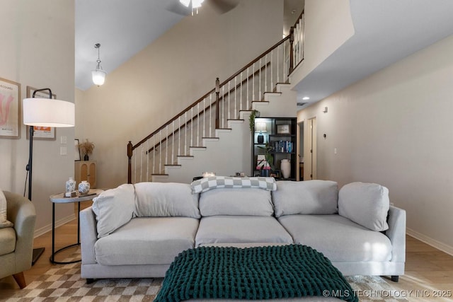 living room featuring a towering ceiling, ceiling fan, and light hardwood / wood-style flooring