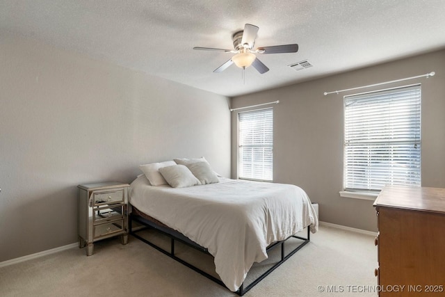 bedroom with ceiling fan, light colored carpet, and a textured ceiling