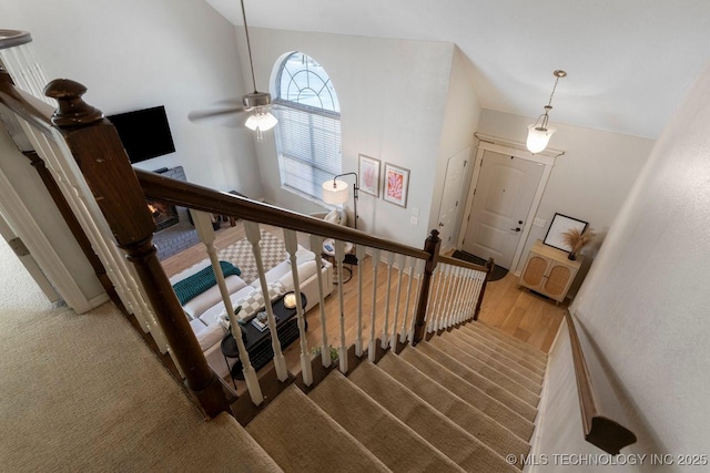 stairs featuring lofted ceiling, hardwood / wood-style floors, and ceiling fan